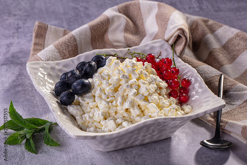 Canvastavla White cottage cheese curd in textured bowl with blueberries and red currants, fr