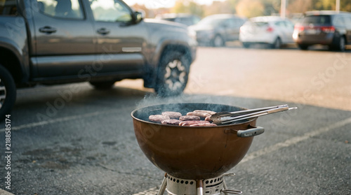 Burgers and sausages grilling on a charcoal barbecue at a tailgate party