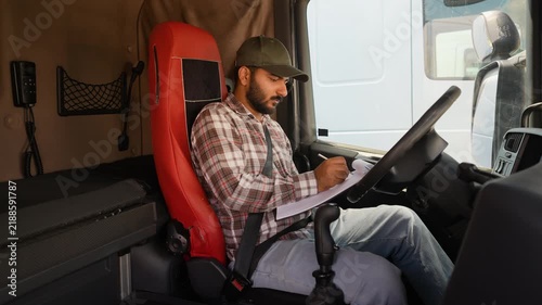 Indian truck driver writing on clipboard in cabin