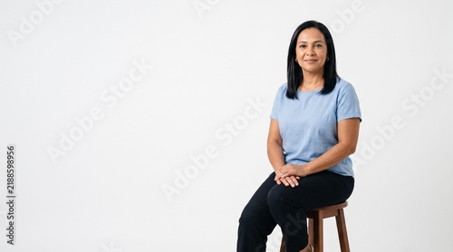 Confident Woman Sitting on Stool Against White Background