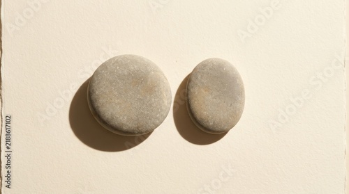 Minimalist pair of smooth river stones on textured paper background