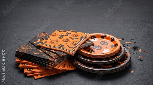 Halloween party supplies including stacked paper plates and napkins with pumpkins ghosts bats and spiderwebs