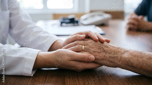 A caring medical professional holding hands with an older person to provide comfort and support in a clinic.