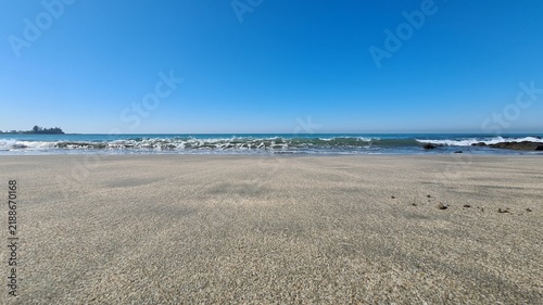 Obraz na płótnie Tranquil coastal vista featuring a wide expanse of sun-kissed sand meeting the g