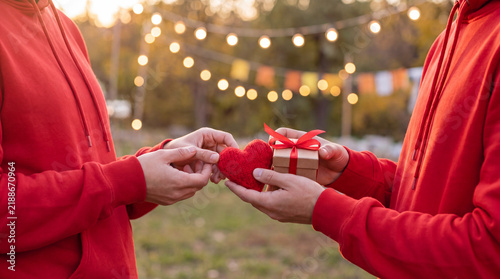 Volunteer hands hold a small red heart and miniature gift box for Giving Tuesday, symbolizing love and generosity in a clean charity campaign.