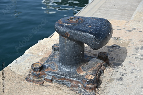 Close Up of a Cast Iron Mooring Bollard in a Harbor with Chairs Nearby