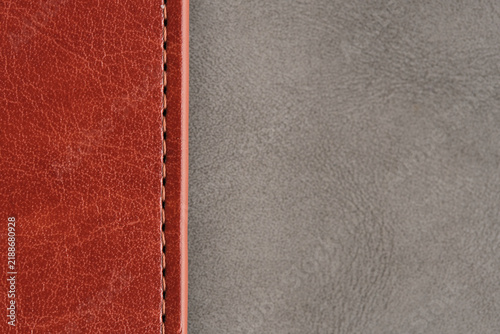 High contrast background showing brown stitched leather seam meeting smooth grey suede surface.