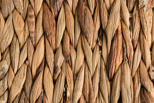 Macro background texture vertically woven natural dried straw or water hyacinth fibers in warm brown.