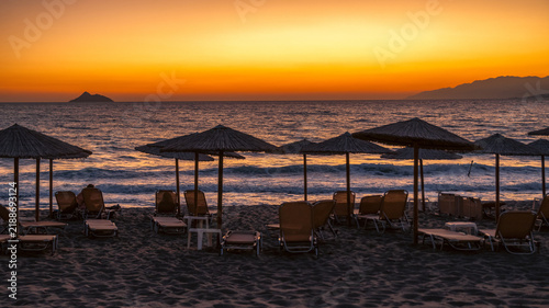 фотографія Sunset over Kalamaki beach in Crete with straw umbrellas, sun loungers and glowi