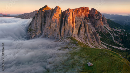 Epic sunrise over Dolomites mountain peaks with low fog valley