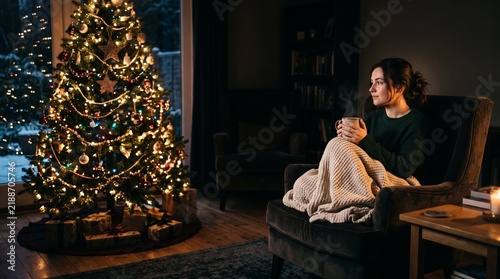 Woman enjoying a warm drink by a decorated Christmas tree on a winter evening Vector Illustration
