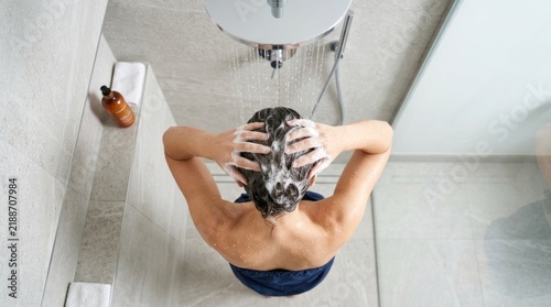 Woman washing her hair with shampoo under a modern shower