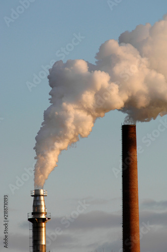Aus dem Kamin einer Industrieanlage strömen Abgase, Rauch und Dampf