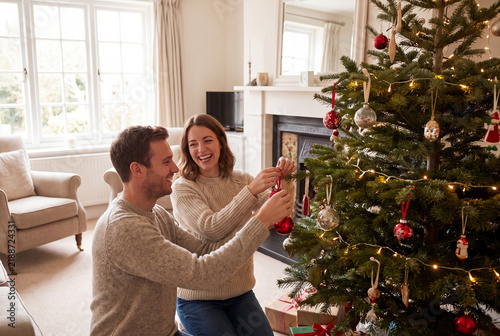 Happy couple decorating christmas tree at home