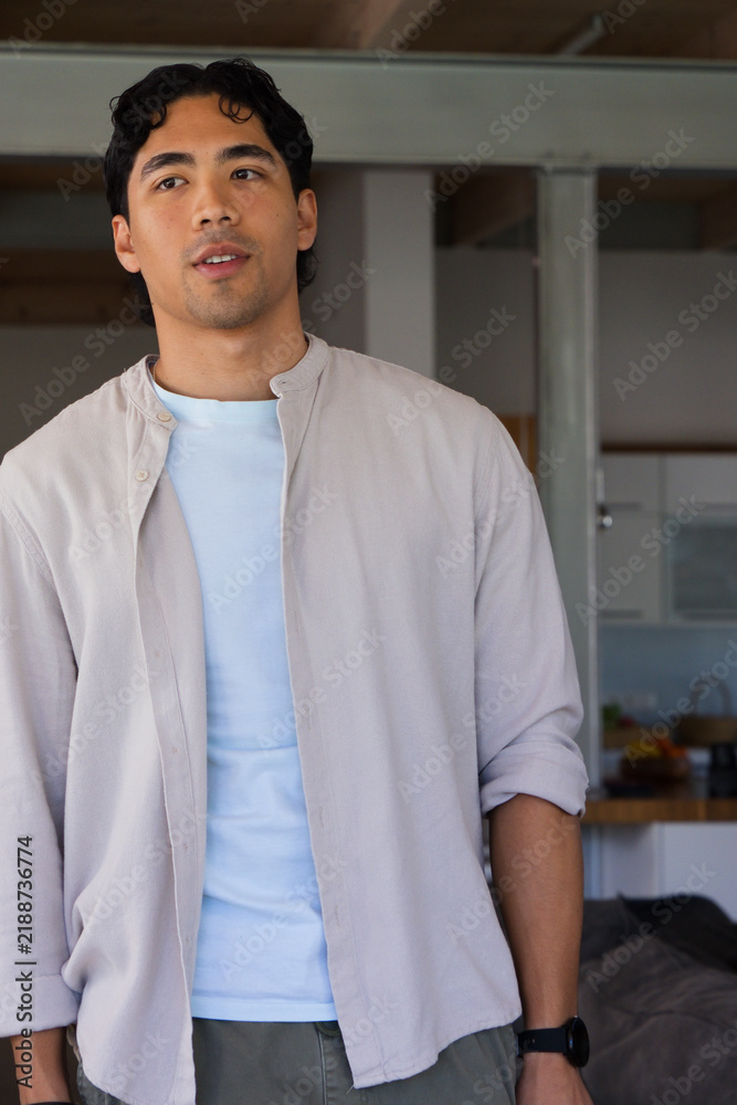 Obraz premium African American man standing in open-plan home, looking up left, wearing beige shirt, black watch