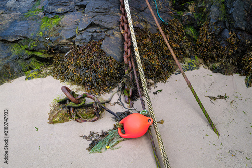 Canvastavla Ropes, rusty chains and a bright orange buoy used for boat berthing sit on the s
