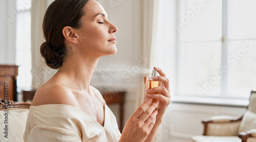 Elegant Woman Applying Perfume in Bright Luxury Interior