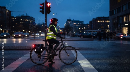 Cyclist wearing safety vest at city intersection at dusk