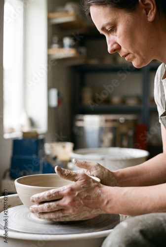 Woman Potter Shaping Clay At Wheel In Profile