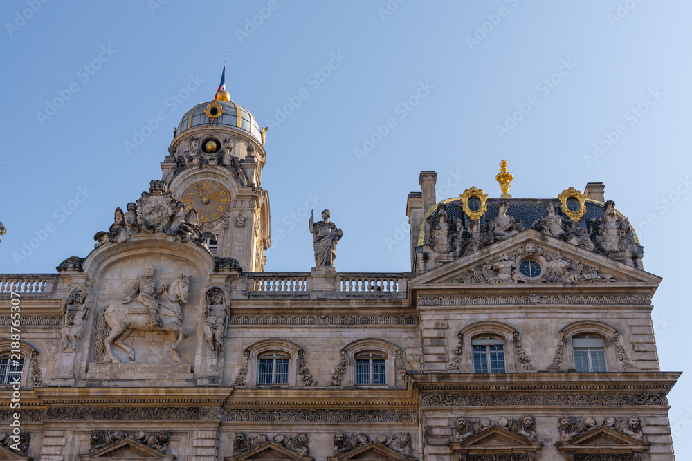 Fototapeta premium Ornate historic building facade with a clock tower and golden dome under blue sky. Lyon