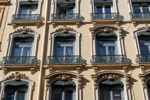 Ornate wrought iron balconies adorn a classic European apartment building facade. Lyon