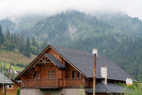 Cozy wooden mountain chalet surrounded by misty pine forests in the Carpathian Mountains, Ukraine. Authentic rural eco-hotel accommodation, luxury cottage real estate, and rainy weather travel destina