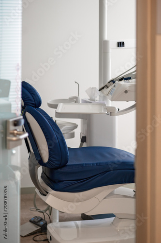 Dental chair with blue upholstery and dental equipment in modern dental clinic interior