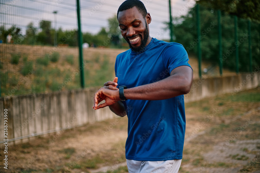 Obraz premium African American man checking fitness tracker during outdoor workout