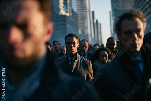 Serious Businessman Standing Out in Busy City Commuter Crowd