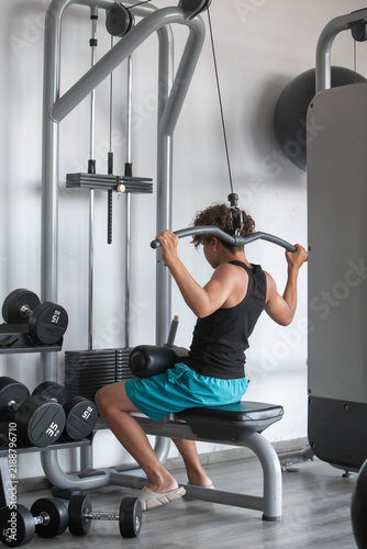 Teenage boy exercising on lat pulldown machine in modern gym. Teenage boy performing a lat pulldown exercise on strength training equipment in a modern gym. Fitness, physical activity, youth sports