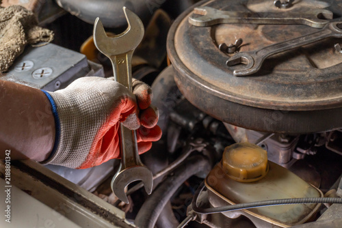 Cuadro en lienzo A gloved hand holds a wrench above an open engine, revealing the intricate details of mechanical work