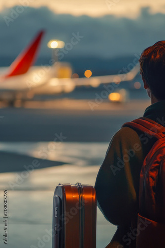 A person examines an airplane from the ground, likely considering a travel or adventure opportunity. vertical frame