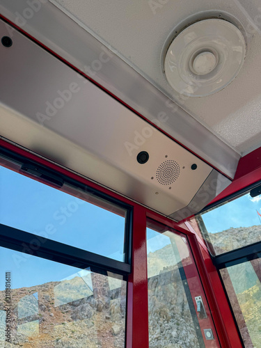 Принти на полотні Interior view of a red cable car with a ceiling speaker and windows showing a mo