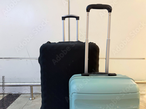фотографія Two pieces of luggage, one black and one light blue, with extended handles posit