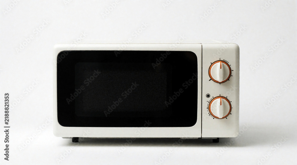 Obraz premium Retro cream microwave oven with black door sits isolated on white background. It has two orange and white control dials for heating food. Small appliance with classic design for kitchen use.