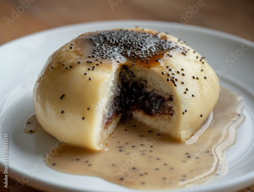 Steamed Germknödel cut open with plum filling and vanilla sauce