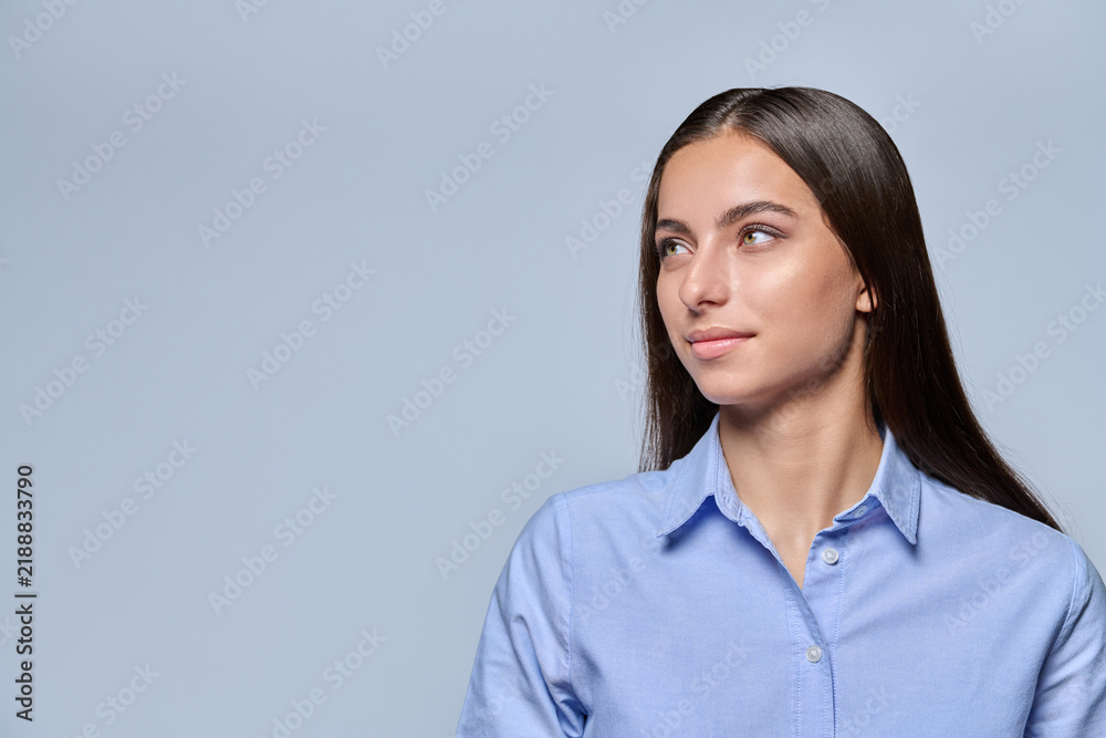 Obraz premium Young female student looking aside with thoughtful expression on light background