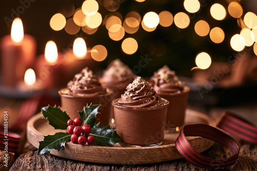 christmas chocolate mousse cups with holly on a wooden tray