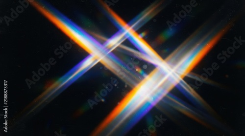 Abstract rainbow light rays crossing in X shape on black background