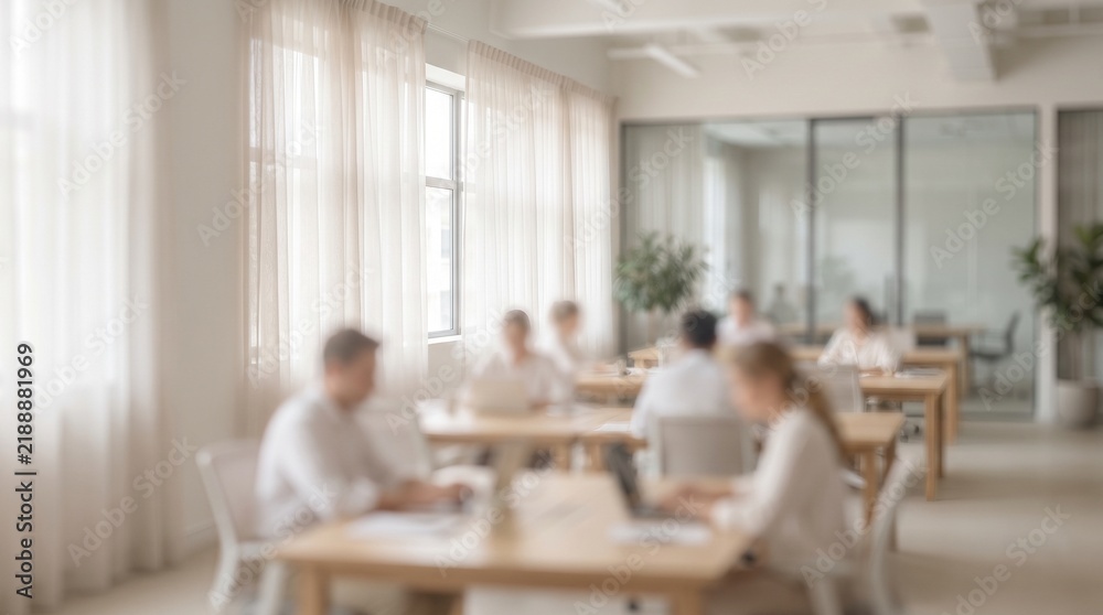 Fototapeta premium Blurred figures collaborate in a modern light filled open office setting