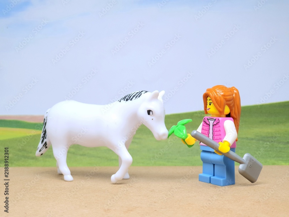 Obraz premium Indonesia - December 1, 2023 : Mini toy figure of people at table with blurred background. Miniature photography concept design. Farmer give green leaves plant.