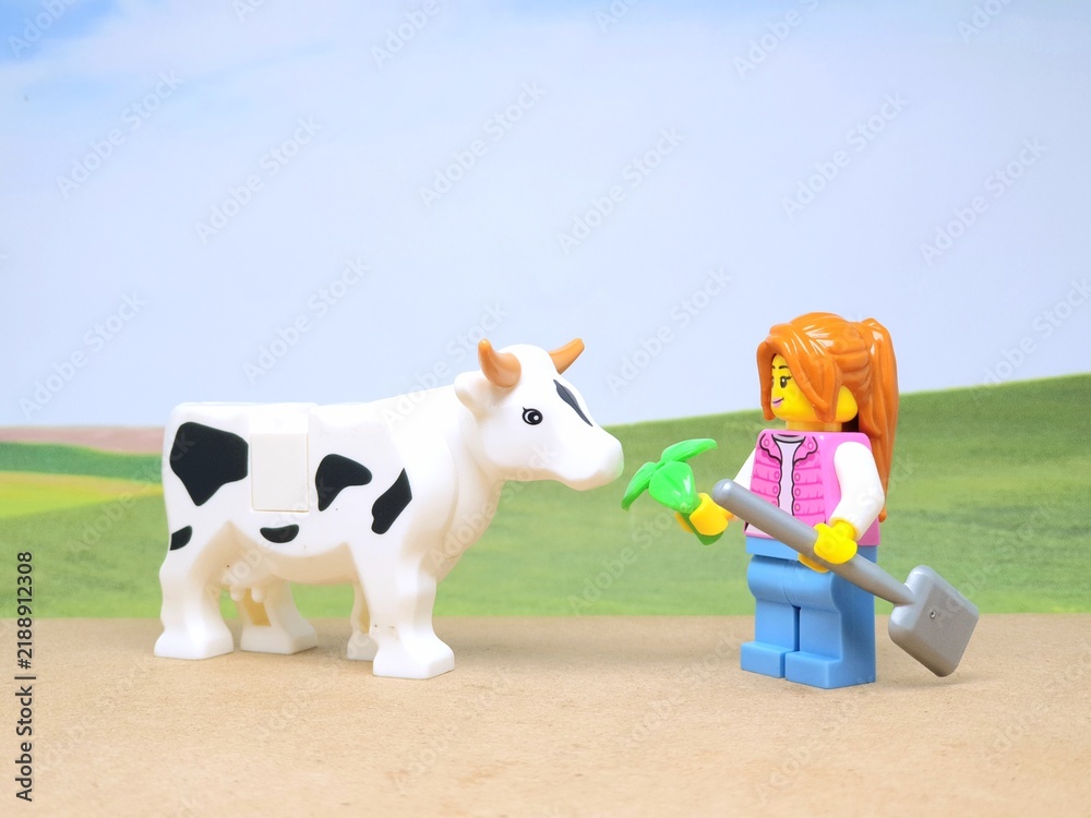 Obraz premium Indonesia - December 1, 2023 : Mini toy figure of people at table with blurred background. Miniature photography concept design. Farmer give green leaves plant.