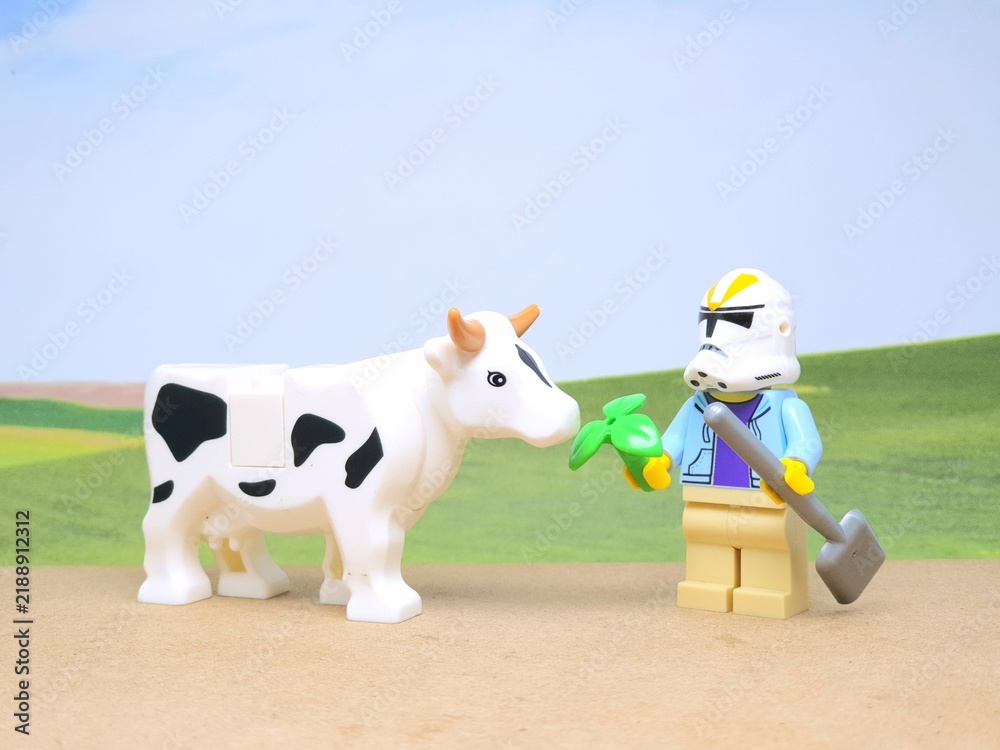 Obraz premium Indonesia - December 1, 2023 : Mini toy figure of people at table with blurred background. Miniature photography concept design. Farmer give green leaves plant.