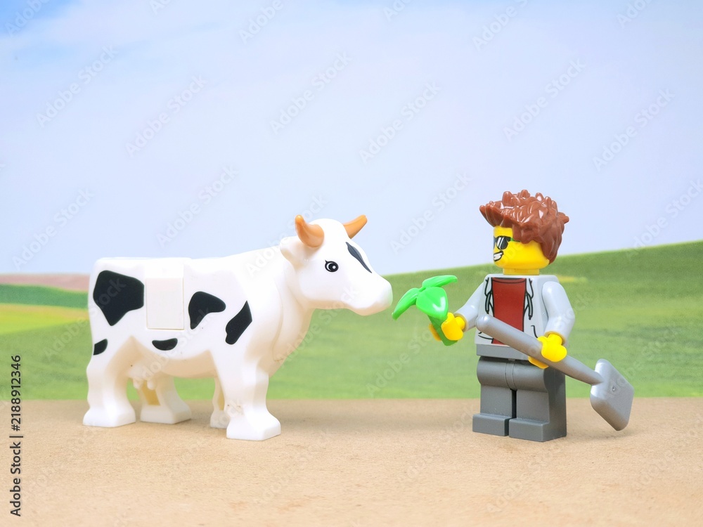 Obraz premium Indonesia - December 1, 2023 : Mini toy figure of people at table with blurred background. Miniature photography concept design. Farmer give green leaves plant.