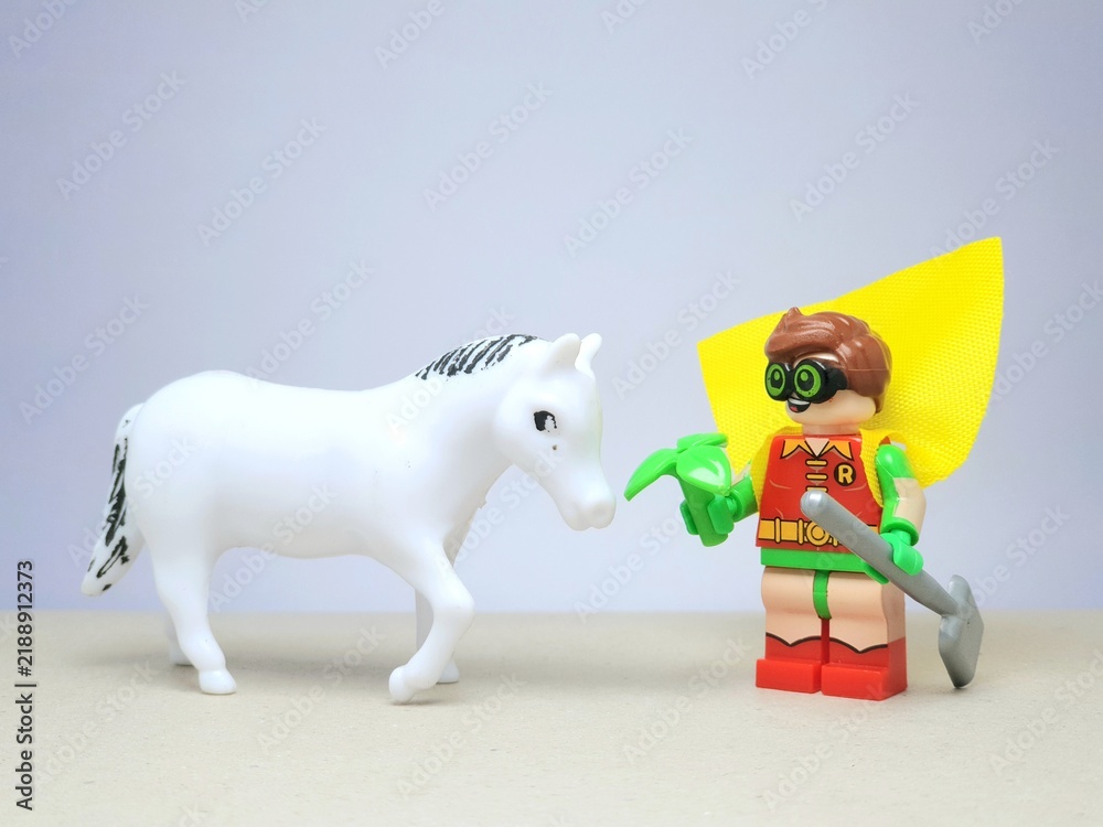 Obraz premium Indonesia - December 1, 2023 : Mini toy figure of people at table with blurred background. Miniature photography concept design. Farmer give green leaves plant.