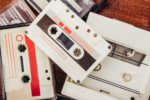Photo of vintage retro cassette player with various audio tapes laying on wooden table, upper view.