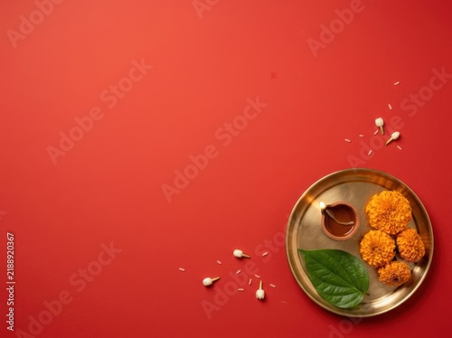 Minimalist Durga Puja and Dussehra devotional flatlay with brass thali, diya, and marigold flowers on a vivid red background with copy space.