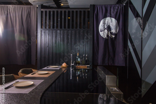 Japanese restaurant setting with black wooden elements and decorative features in the evening