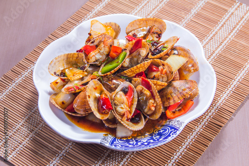 Seafood dish with clams and vegetables served in a bowl on a table