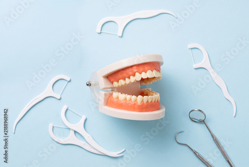 Dental Care Flat Lay with Teeth Model, Floss Picks and Dentist Tools on Blue Background